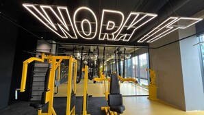 A gym with mirrored walls, yellow exercise equipment, and a neon sign that reads "WORK IT". - Chillout Dorm Cracow (Kraków)