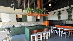 A modern kitchen with green cabinets, a central island with stools, and hanging plants. - Chillout Dorm Cracow (Kraków)