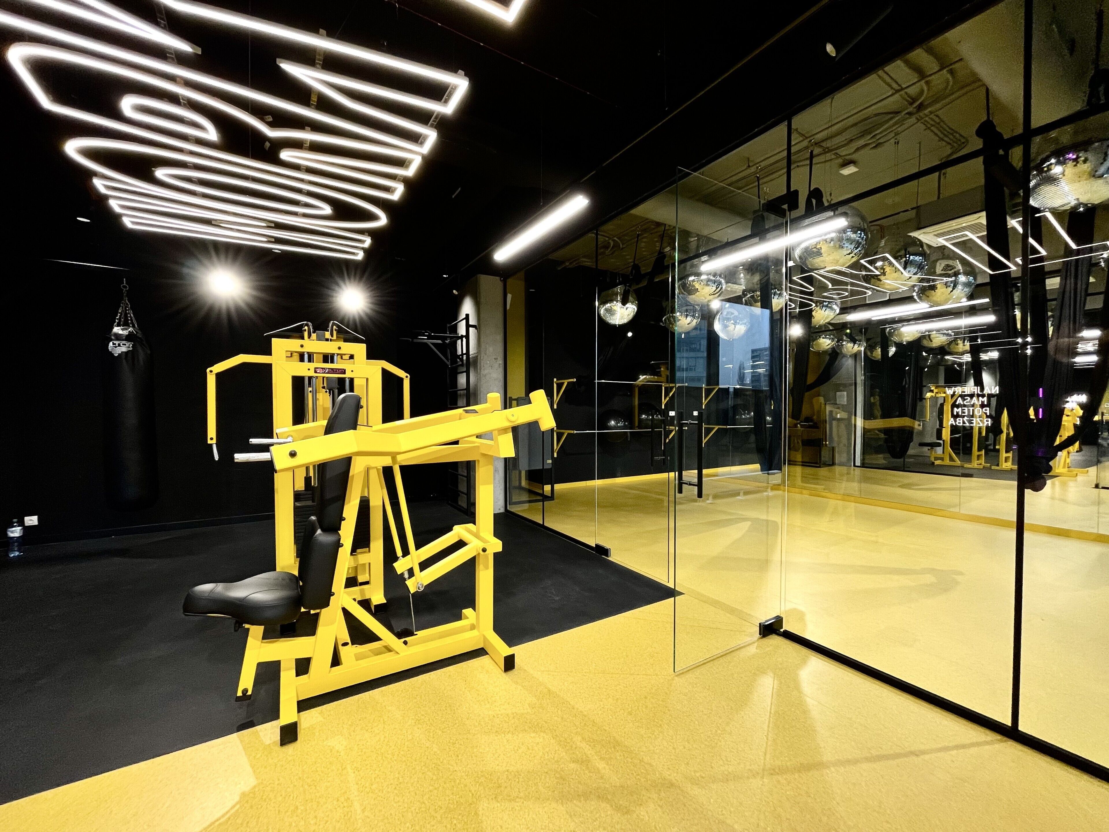 A gym with mirrored walls, exercise equipment, and a punching bag.