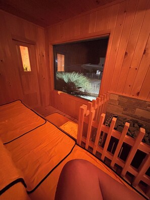 Una cabaña de madera con un ventanal grande, una terraza de madera y una chimenea de piedra.