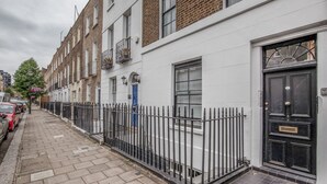 A row of terraced houses with a black metal fence, a blue door, and a number plate. - Convenient Marylebone 1BR, close to Pubs & Restaurants, by Blueground (London)