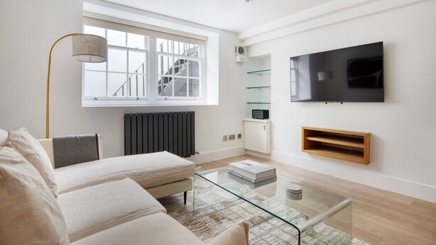 A modern living room with a sofa, coffee table, and a TV mounted on the wall. - Convenient Marylebone 1BR, close to Pubs & Restaurants, by Blueground (London)