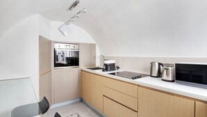 A compact kitchen with a built-in oven, a stovetop, and a microwave. There is a sink with a faucet, and a kettle on the counter. - Convenient Marylebone 1BR, close to Pubs & Restaurants, by Blueground (London)