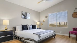 A bedroom with a bed, two bedside tables, a ceiling fan, a window with blinds, and a wall clock. - Prime Location, Perfect Stay: Stadium Proximity Home with Pool & Entertainment! (Glendale)
