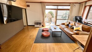 Ein modernes Wohnzimmer mit Holzboden, einer Ledersofa, einem Couchtisch und einem Flachbildfernseher.