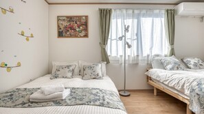 Un dormitorio con cama, mesita de noche, lámpara de pie y ventana con cortinas.