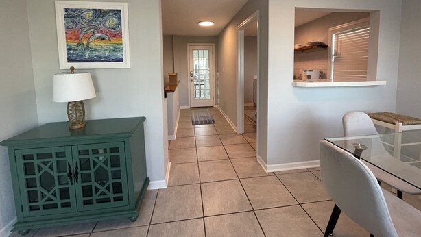 A modern kitchen with a glass table, a teal cabinet, and a painting on the wall. - Dolphin View House #2 (Eastpoint)