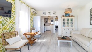 A modern living room with a sofa, a dining table, and a kitchen in the background. - Fener de Dalt 90 - Apartment with spectacular view (Llança)