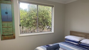 A bedroom with a large window, a bed with striped bedding, and a painting on the wall. - Hideaway By The Lake - The perfect lakeside holiday location!
 (Nords Wharf)