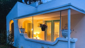 Une maison moderne dotée d’une grande fenêtre, d’un petit porche et d’une porte avec un panneau de verre.