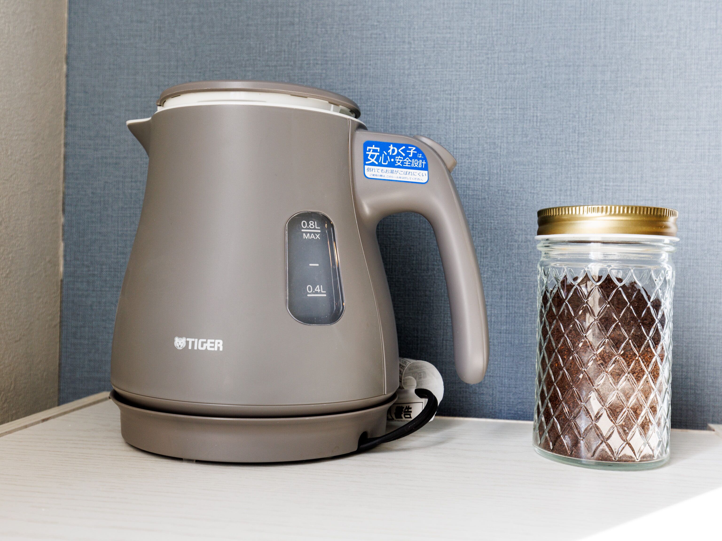 A modern electric kettle with a digital display and a stainless steel container beside it.