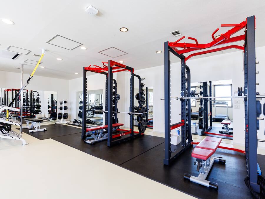 Un gimnasio con equipo de levantamiento de pesas, cintas de correr y un espejo.