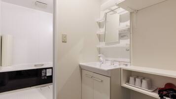 A compact bathroom with a white sink, mirror, and storage shelves.