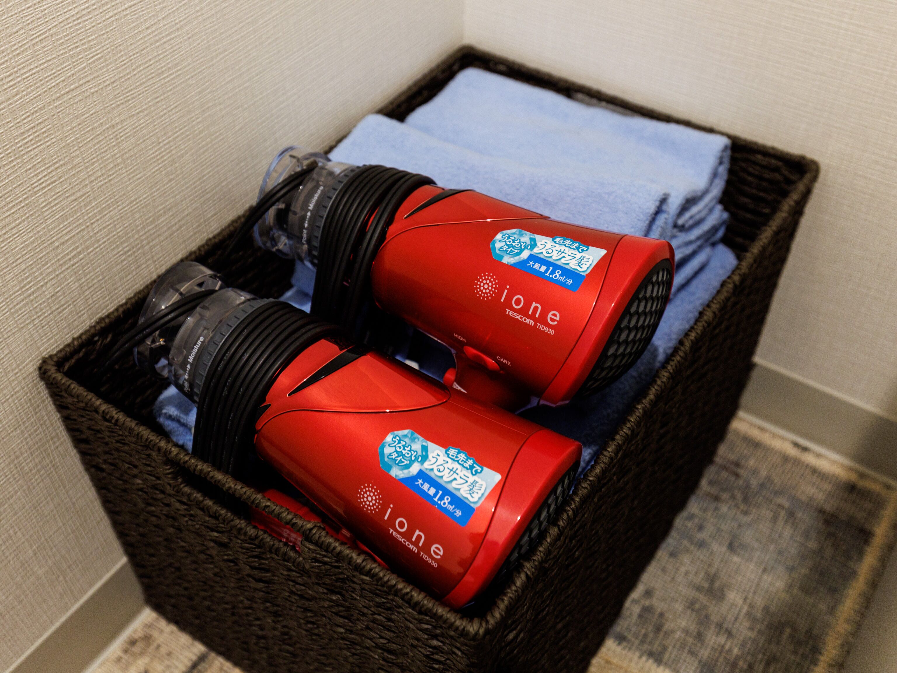 A wicker basket containing two red iOne portable heaters and a folded blue towel.