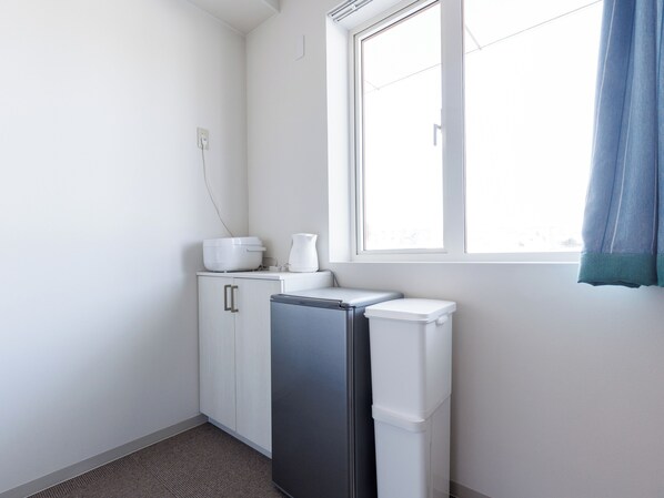 Una pequeña kitchenette con un refrigerador, un microondas y una cafetera sobre una encimera.