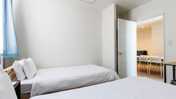 Quarto de hotel moderno com duas camas de solteiro, uma escrivaninha e uma cadeira.