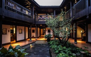 A traditional courtyard with a central pathway, wooden railings, and potted plants. - Lijiang Old Town Anyu Hotel  (Lijiang)
