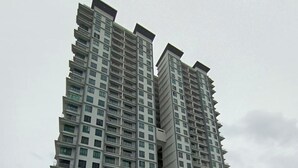 A high-rise residential building with a swimming pool in the foreground.