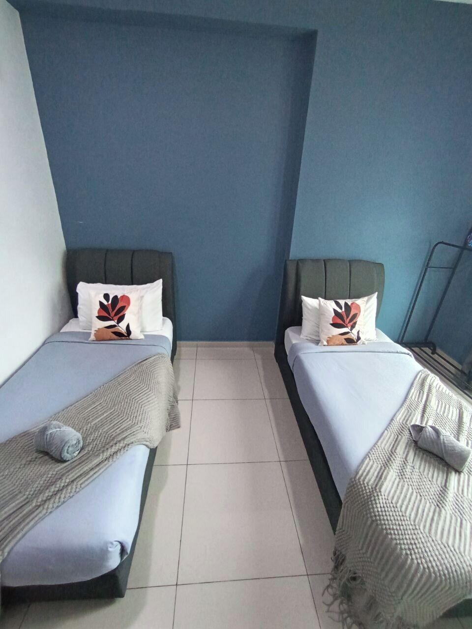 A room with two beds, each with a pillow and a blanket.