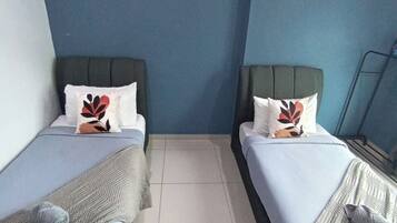 A room with two beds, each with a pillow and a blanket.