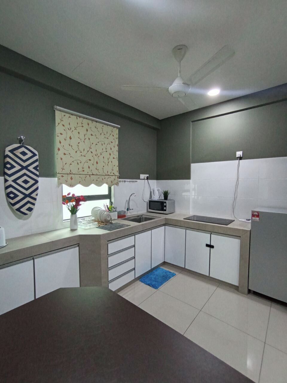 Cozinha com micro-ondas, pia e ventilador de teto.