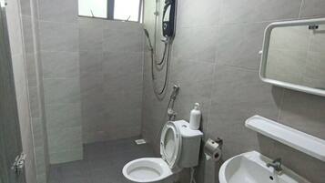 A bathroom with two toilets, a sink, a shower, and a window.