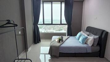 A bedroom with a bed, a ceiling fan, a window with curtains, and a view of the city.