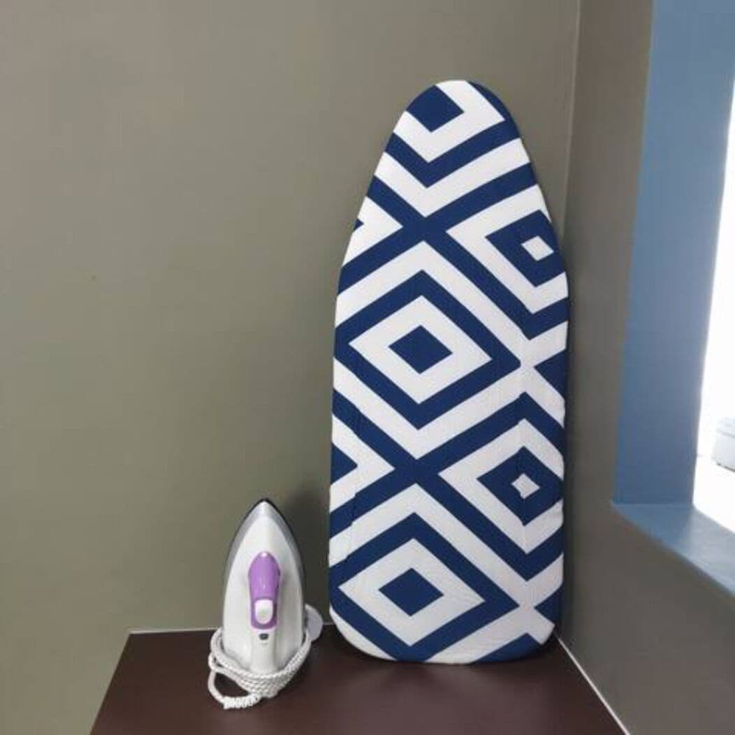 Una tabla de planchar estampada y un planchador sobre una superficie oscura.