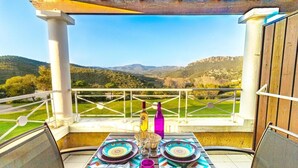 Une table dressée à l’extérieur, offrant une vue panoramique sur des collines et un ciel dégagé.