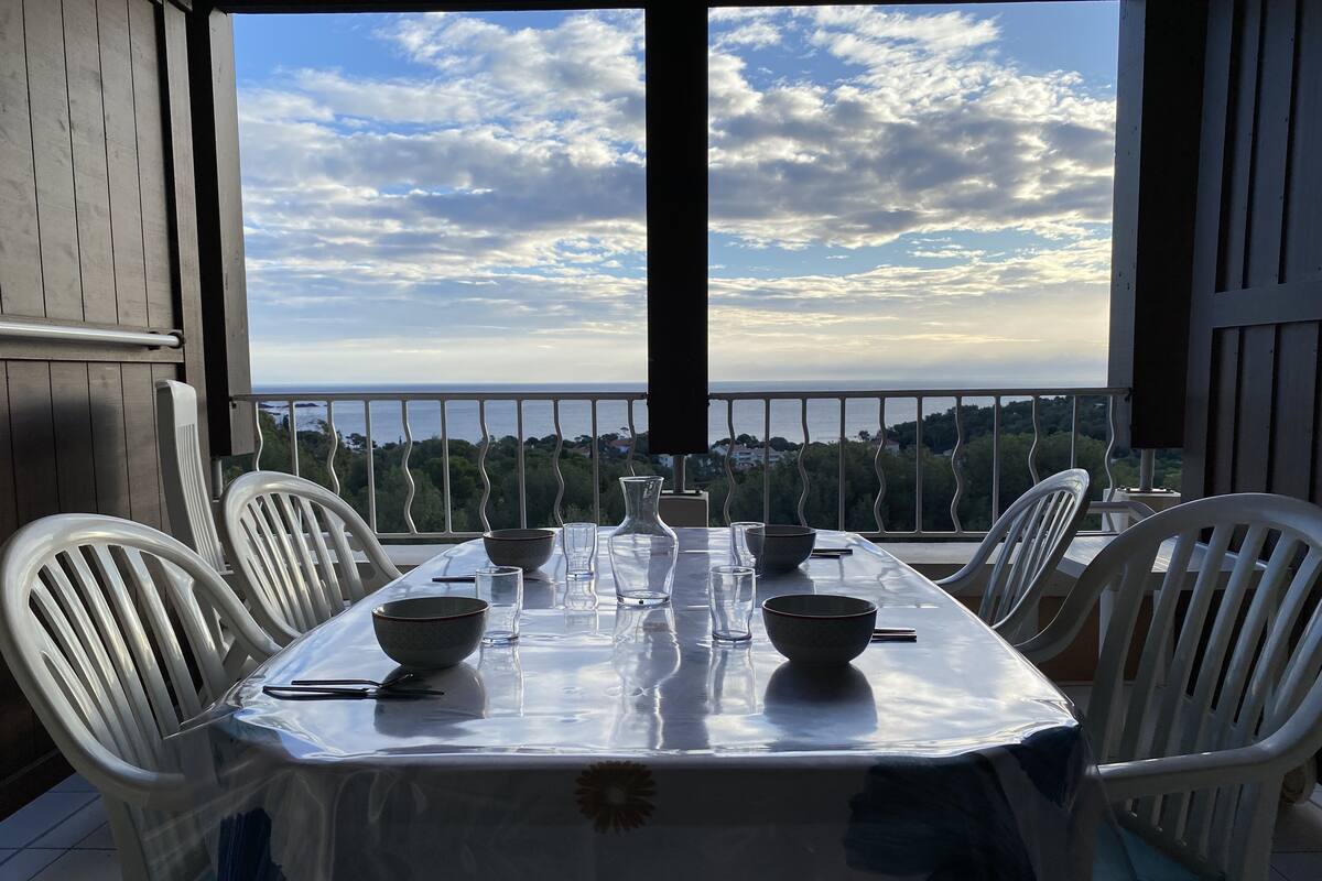 A table set for four with a view of the sea and trees.