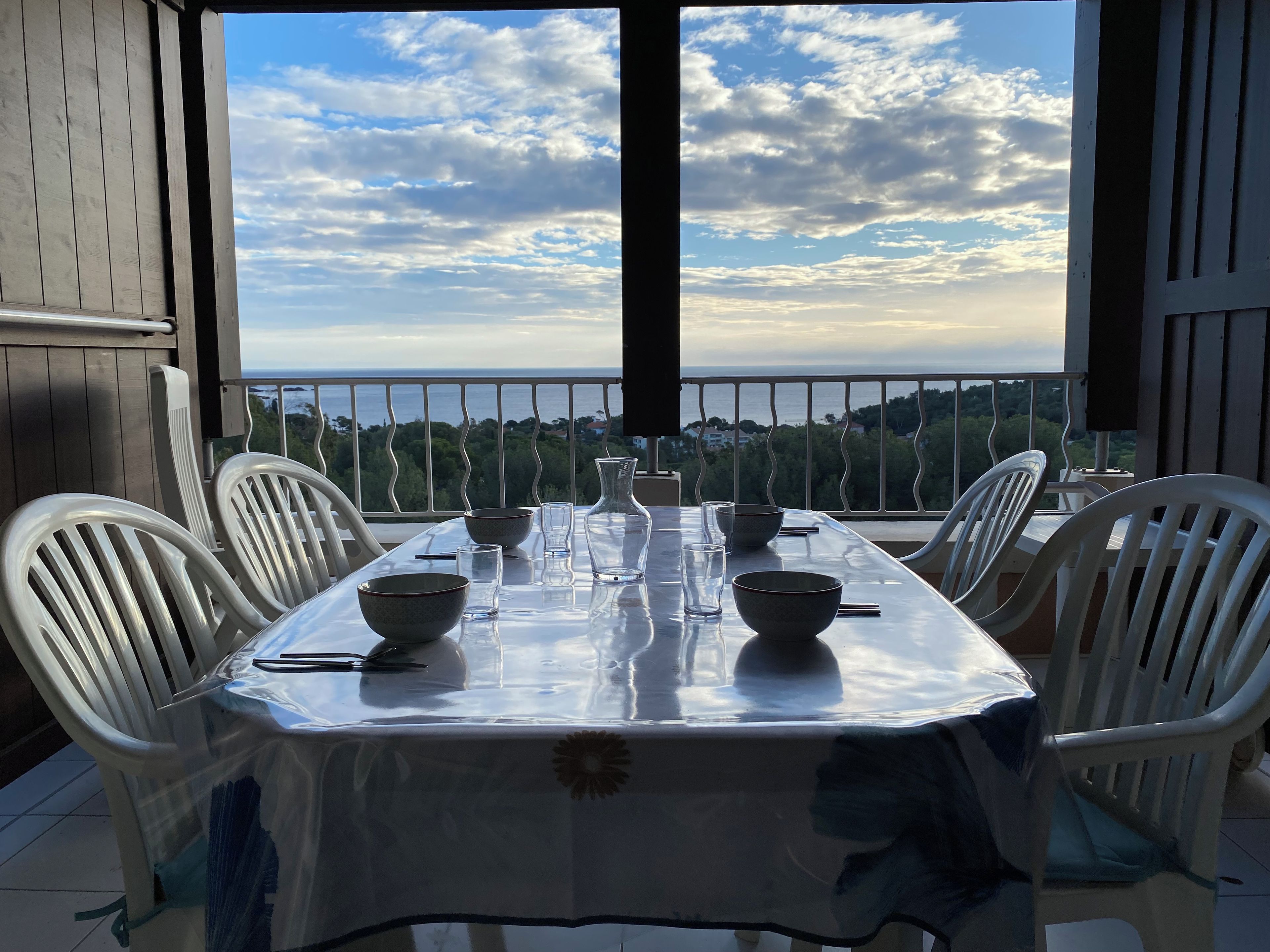 Tavola imbandita per quattro con vista sul mare e sugli alberi.