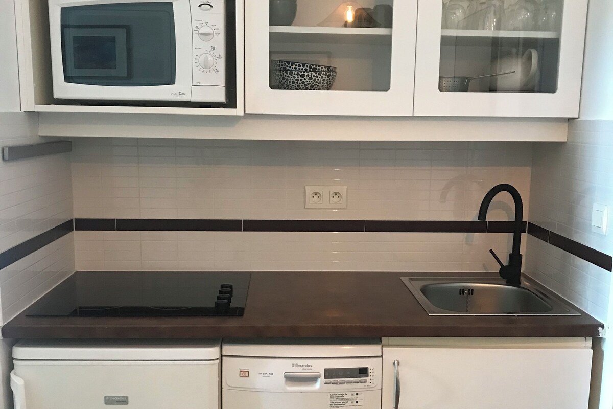A compact kitchen with a microwave, dishwasher, and a sink with a faucet.