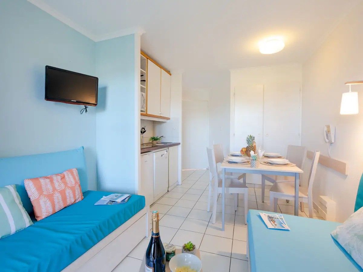 Une pièce de taille modeste comprenant un lit, une petite table à manger et un téléviseur fixé au mur.