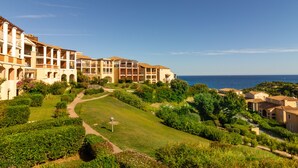 Un hôtel situé sur la côte, composé de plusieurs bâtiments, doté d’un jardin bien entretenu et offrant une vue dégagée sur la mer.