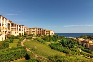 Un resort con edificios de varios pisos, un jardín cuidado y vistas al mar.