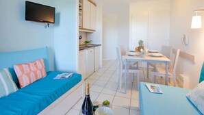 Une pièce de taille modeste comprenant un lit, une petite table à manger et un téléviseur fixé au mur.