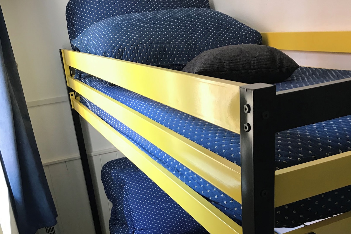 Un lit superposé avec une literie bleue et un oreiller noir.