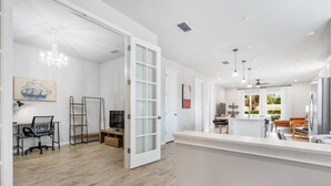 Una cocina amplia y moderna con armarios blancos, una isla central e iluminación colgante.
