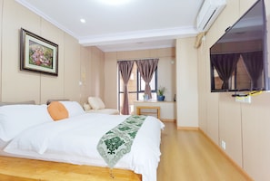 A hotel room with a large bed, a TV mounted on the wall, a window with curtains, and a small table with a plant. - Orange Mingwu Hotel (Chengdu)
