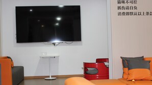 Una sala de estar moderna con un televisor de pantalla plana montado en la pared, una mesita blanca y sofás naranja y grises.
