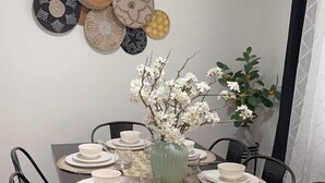 A dining table set for six with a vase of white flowers in the center, surrounded by black chairs.
