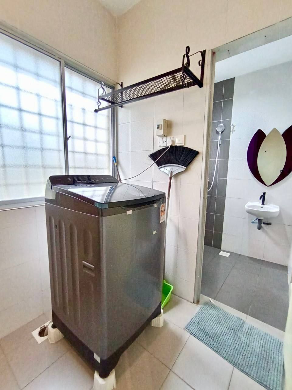 A compact kitchen with a built-in washing machine, a broom, and a sink.