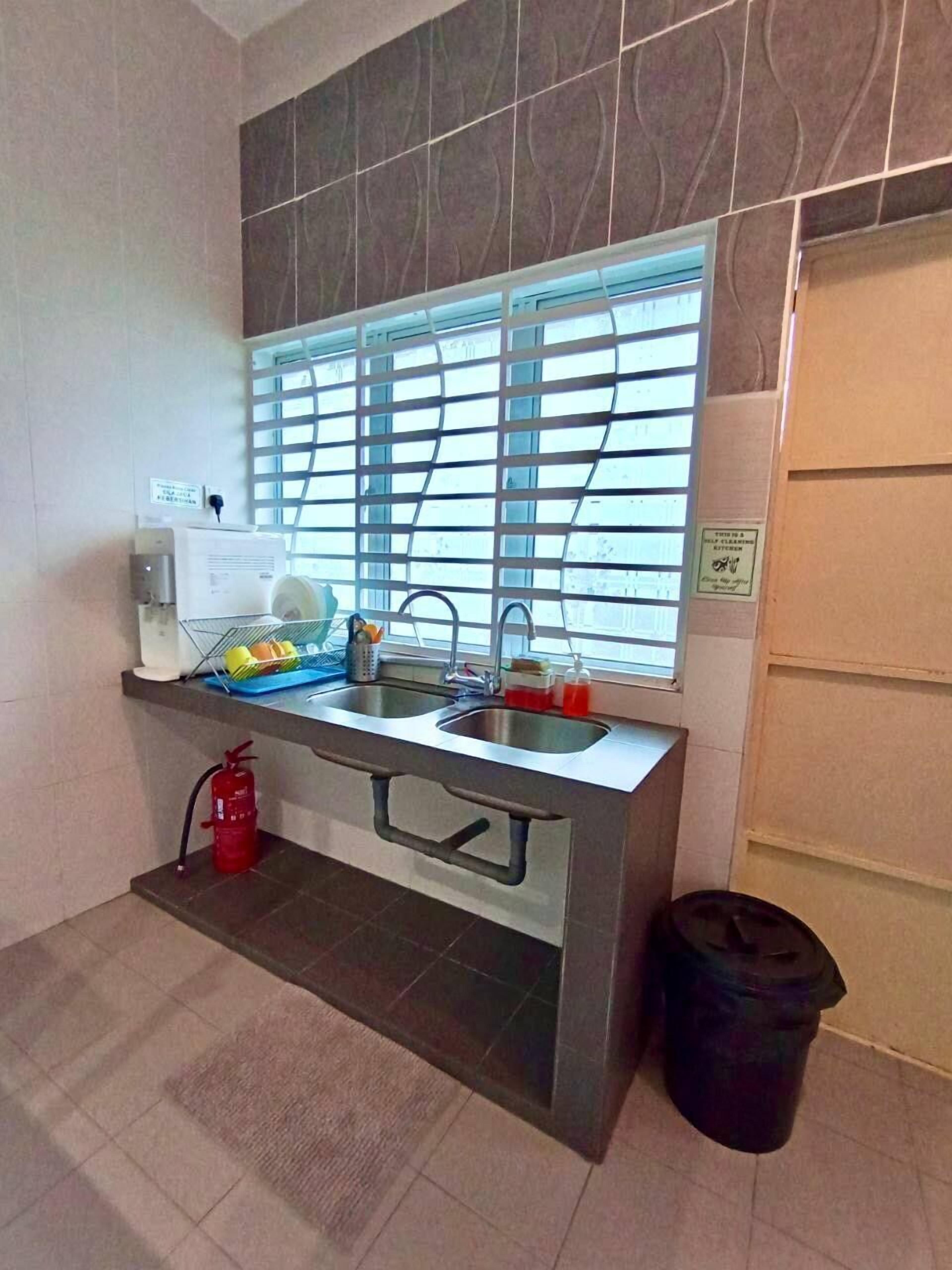 A compact kitchenette with a window, a sink, a small countertop, and a fire extinguisher.