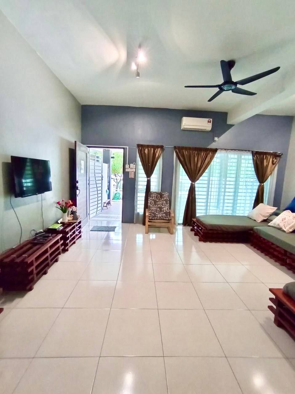 A spacious living room with a flat-screen TV, a ceiling fan, and a sofa.