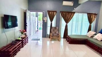 A spacious living room with a flat-screen TV, a ceiling fan, and a sofa.