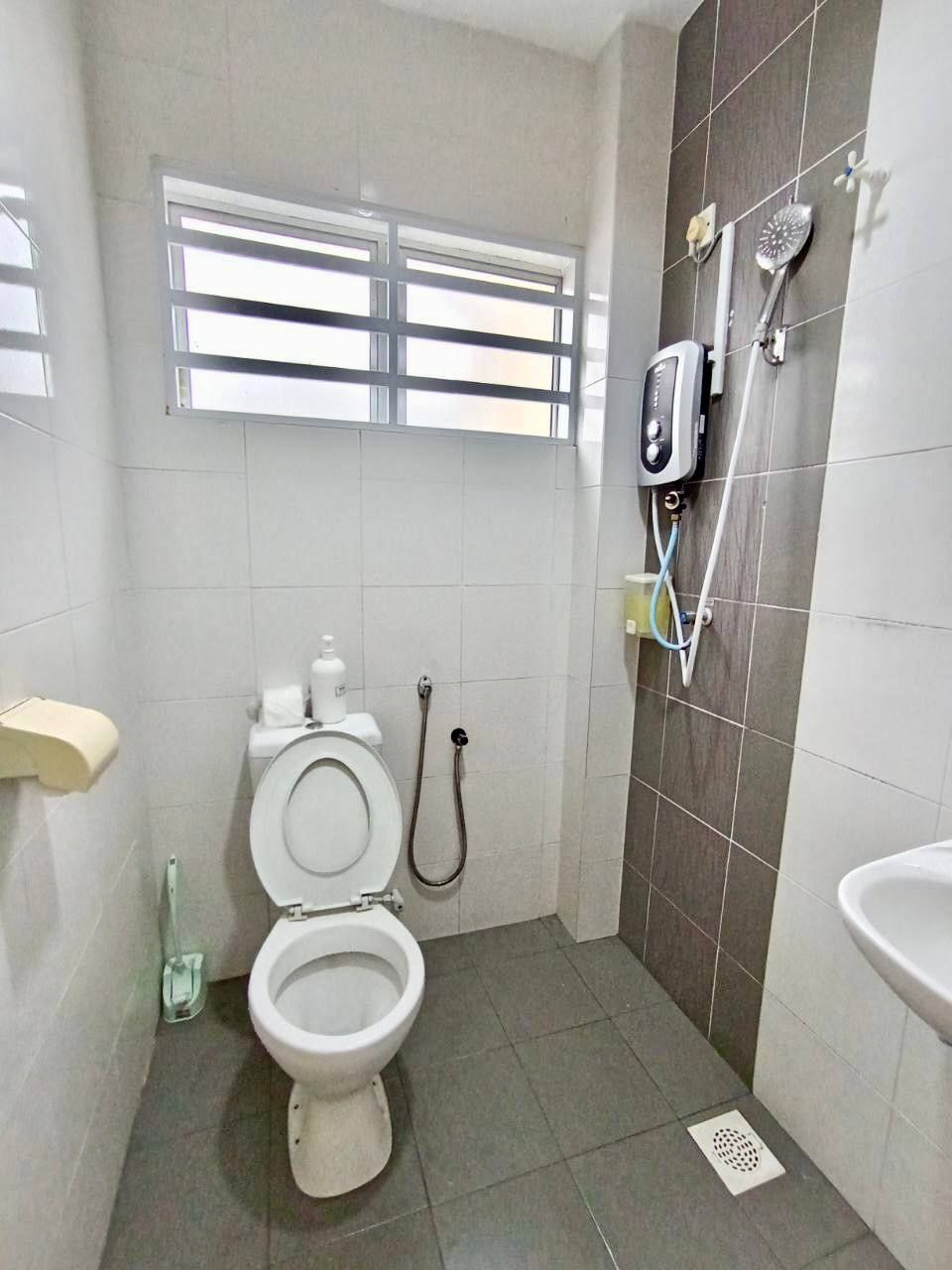 A bathroom with a toilet, a shower, and a sink.