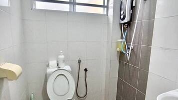 A bathroom with a toilet, a shower, and a sink.