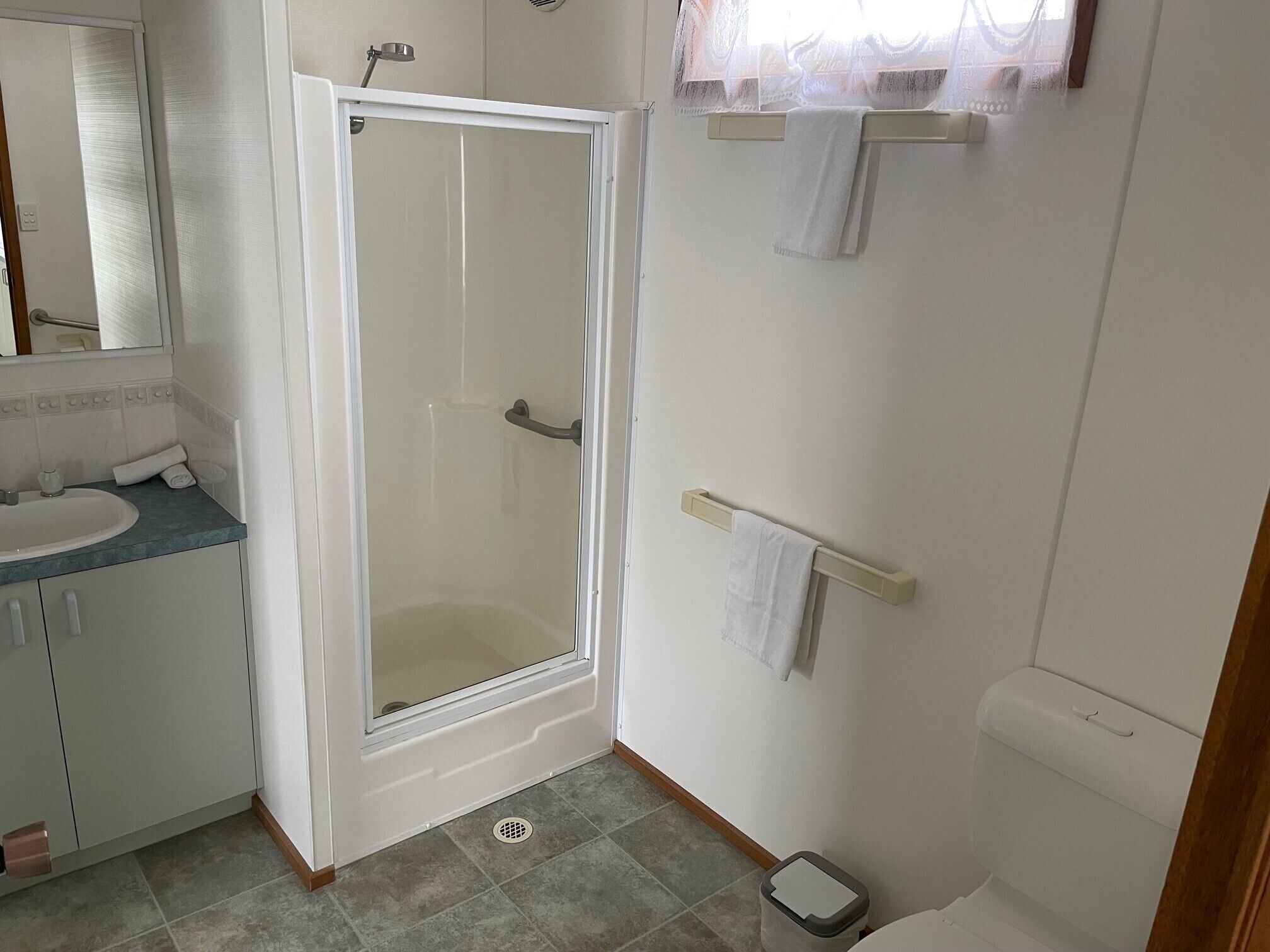 Un baño con ducha, lavabo, inodoro y toallero.