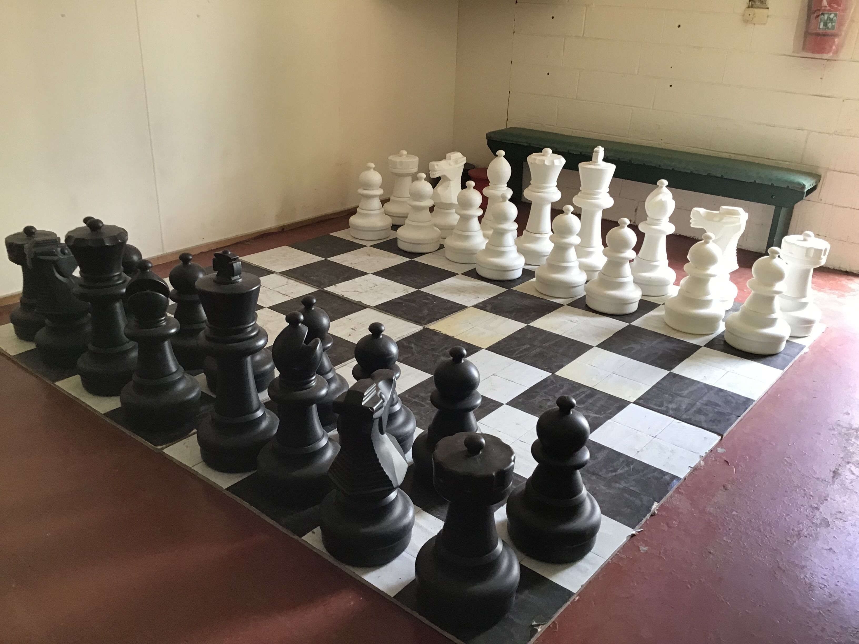 A checkered floor with chess pieces arranged for a game.