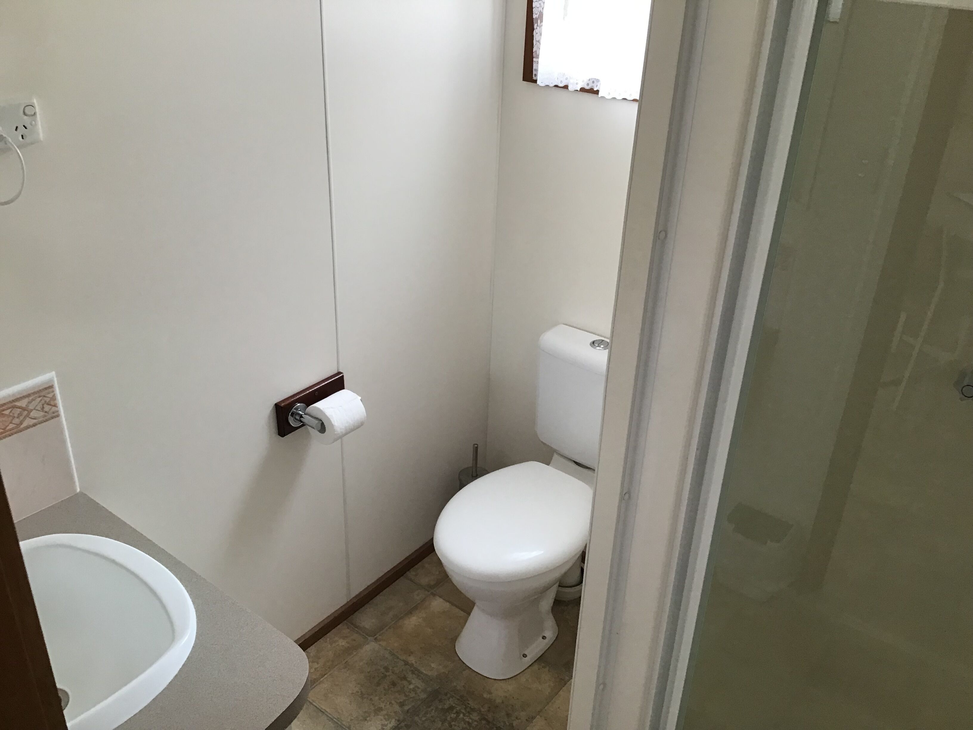 Une petite salle de bain compacte comprenant des toilettes, un lavabo et un espace douche.